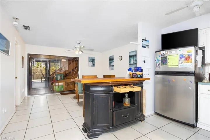 Kitchen with ceiling fan, freestanding refrigerator, light tile patterned floors, butcher block countertops, and a textured ceiling