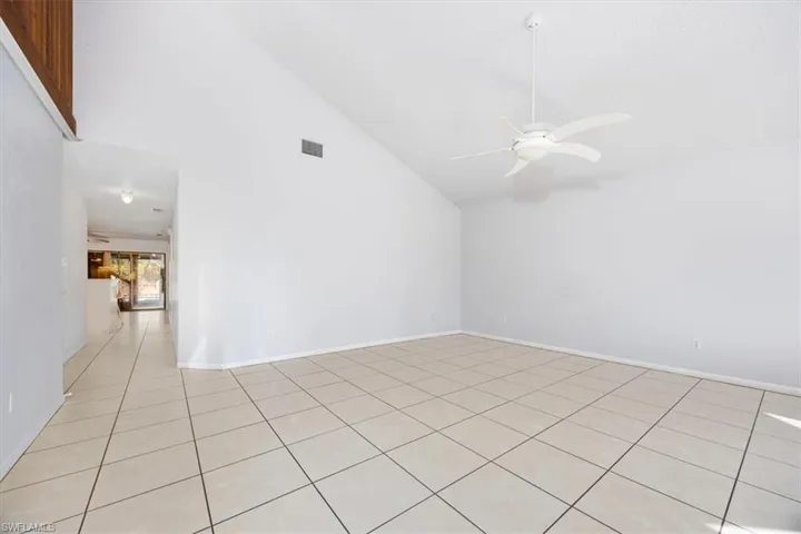 Empty room featuring ceiling fan, lofted ceiling, and light tile patterned floors