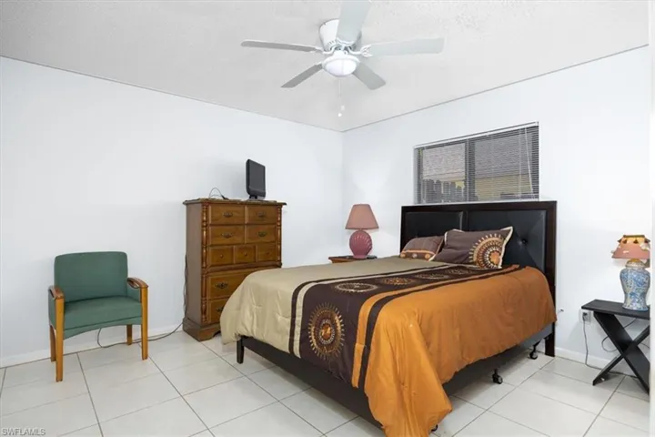Tiled bedroom with ceiling fan and a textured ceiling