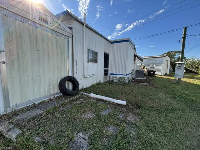 View of rear of property featuring a lawn and a storage unit