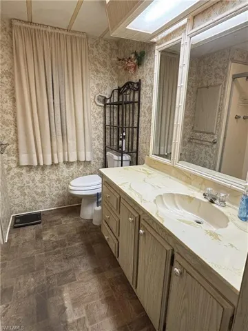 Bathroom featuring vanity and wallpapered walls