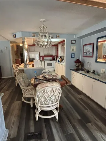 Dining area featuring  wood look vinyl flooring, built in breakfront & pretty chandelier.