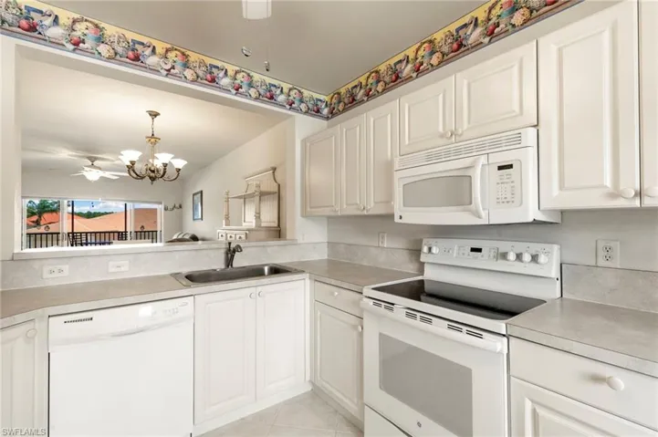 Kitchen with white appliances, a sink, a chandelier, and light countertops