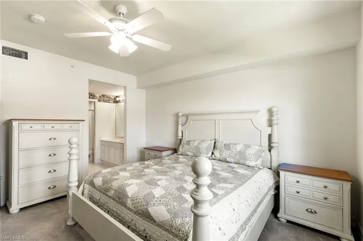 Bedroom with dark carpet, ceiling fan, and ensuite bathroom