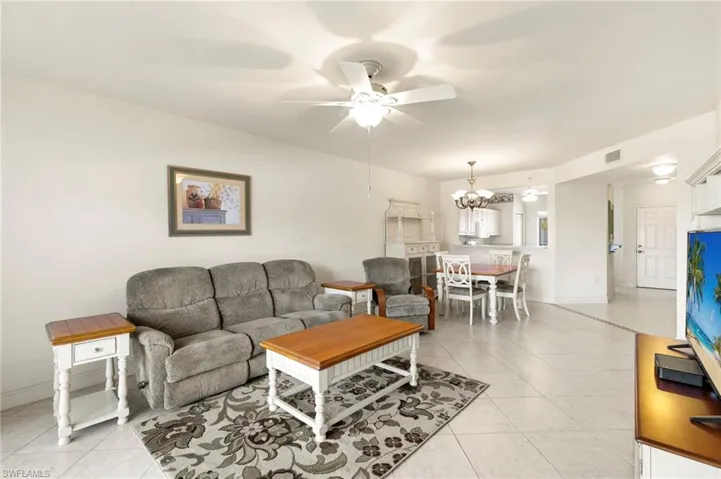 Living area featuring light tile patterned floors, ceiling fan, and a chandelier