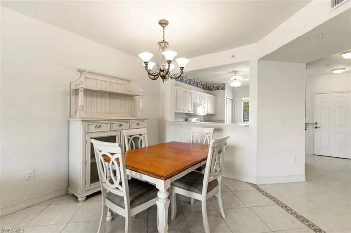 Dining area featuring a chandelier, baseboards, light tile patterned floors, and a ceiling fan