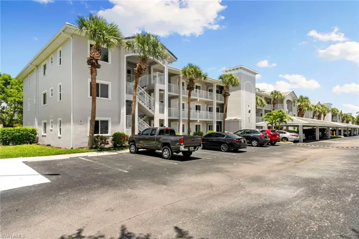View of apartment building / complex featuring uncovered parking