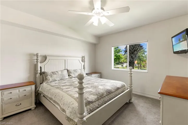 Bedroom featuring light carpet, a ceiling fan, and baseboards