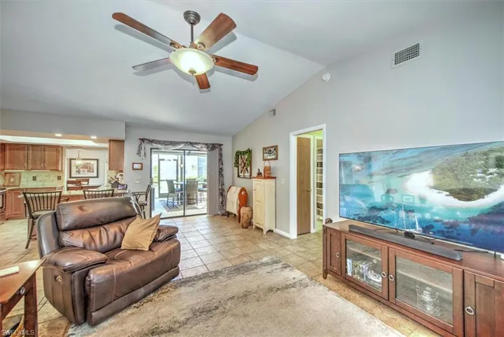 Tiled living room with ceiling fan and lofted ceiling