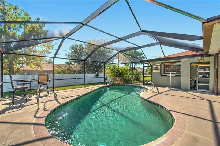 View of swimming pool with glass enclosure and a patio