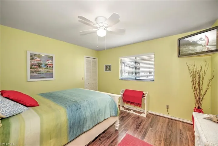 Bedroom with ceiling fan, a closet, and wood-type flooring