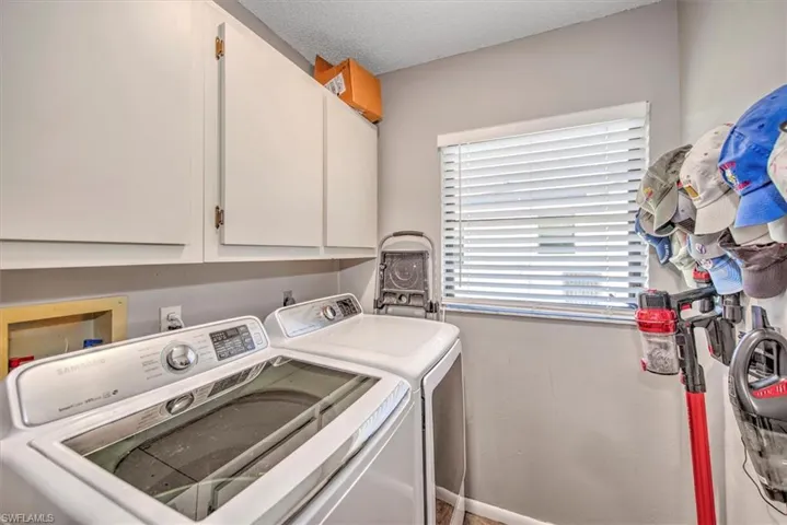 Laundry room with washer and dryer, cabinets, and a textured ceiling