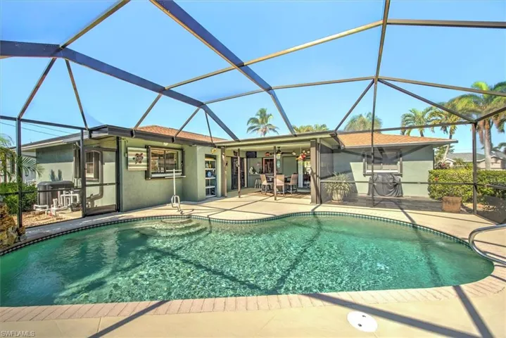 View of pool with a lanai, grilling area, ceiling fan, and a patio