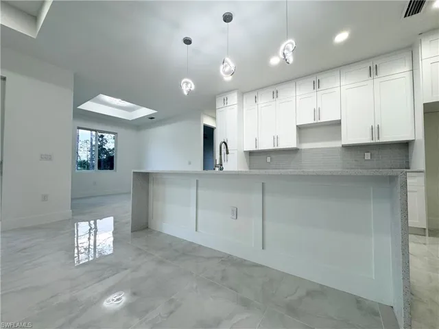Kitchen featuring white cabinets, marble finish floor, and tasteful backsplash