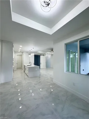 Spare room with a barn door, a sink, marble finish floor, a ceiling fan, and baseboards