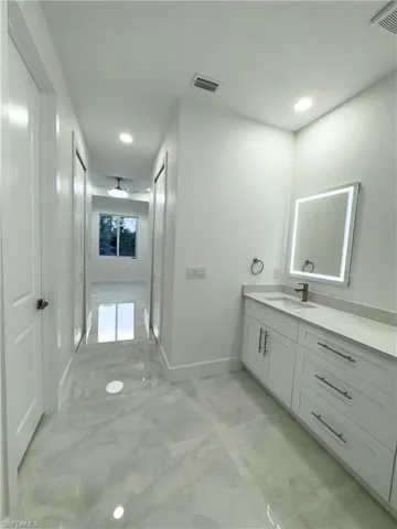 Bathroom featuring visible vents, marble finish floor, baseboards, and vanity