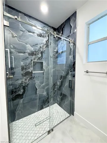 Bathroom with baseboards, marble finish floor, and a marble finish shower