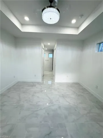 Spare room with baseboards, a tray ceiling, recessed lighting, and marble finish floor
