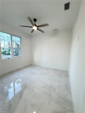 Unfurnished room with ceiling fan, visible vents, baseboards, and marble finish floor