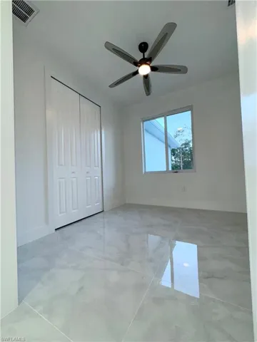 Unfurnished bedroom featuring visible vents, a closet, marble finish floor, baseboards, and ceiling fan