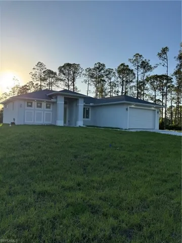View of front of home with a garage, a front lawn, and stucco siding