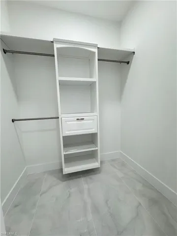 Spacious closet featuring marble finish floor