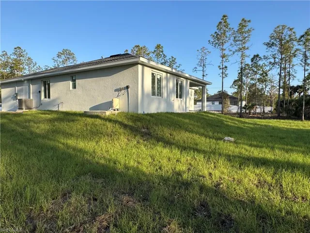 View of home's exterior with a lawn, central AC, and stucco siding