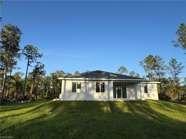Back of property with a lawn and stucco siding