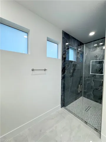 Bathroom with baseboards, marble finish floor, a marble finish shower, and recessed lighting