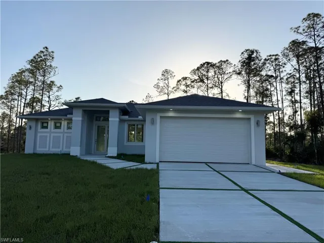 View of front of property featuring an attached garage, a front lawn, stucco siding, and concrete driveway