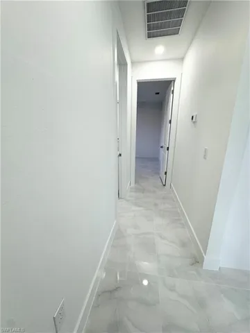 Corridor featuring recessed lighting, baseboards, marble finish floor, and visible vents