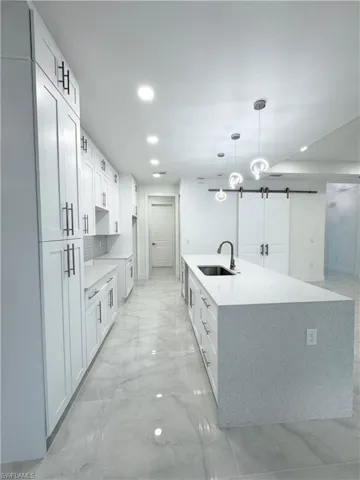 Kitchen featuring recessed lighting, a sink, marble finish floor, and a large island