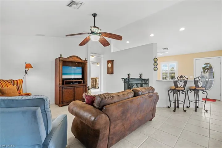 Tiled living room with ceiling fan and lofted ceiling