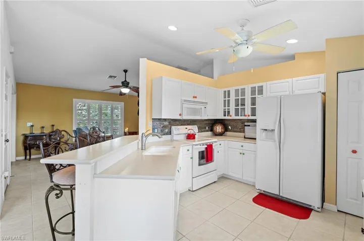 Kitchen with white cabinetry, sink, white appliances, and kitchen peninsula