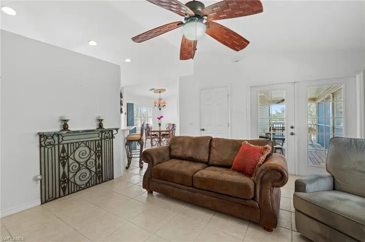 Tiled living room with french doors, ceiling fan, and lofted ceiling