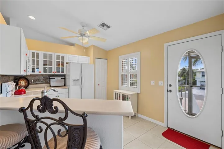 Kitchen featuring white cabinetry, white appliances, lofted ceiling, and light tile patterned floors