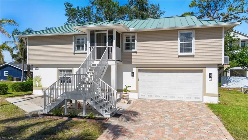 View of front facade featuring a garage, a sunroom, and a front lawn