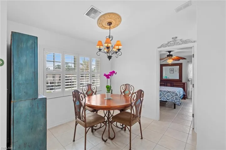 Tiled dining room featuring ceiling fan with notable chandelier