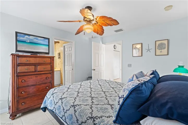 Bedroom with ceiling fan, connected bathroom, and light tile patterned floors