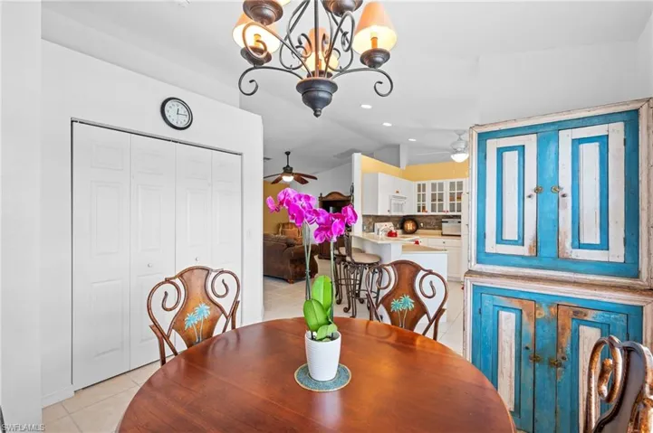Tiled dining area featuring lofted ceiling and ceiling fan with notable chandelier