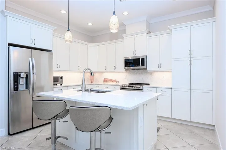 Kitchen featuring white cabinets, appliances with stainless steel finishes, hanging light fixtures, and sink