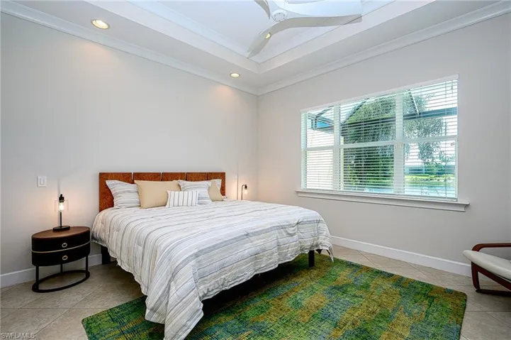 Tiled bedroom featuring crown molding, a tray ceiling, and ceiling fan