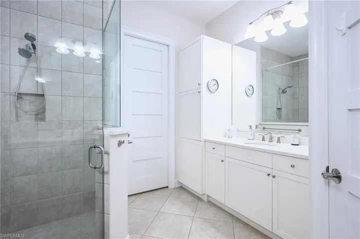 Bathroom featuring a shower with shower door, tile patterned flooring, and vanity