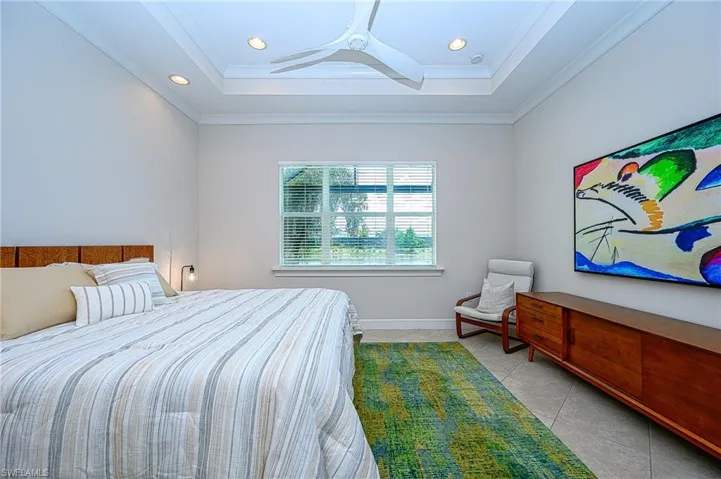 Bedroom featuring crown molding, a raised ceiling, ceiling fan, and light tile patterned flooring