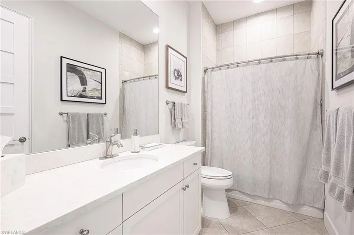 Full bathroom featuring shower / bathtub combination with curtain, tile patterned flooring, toilet, and vanity