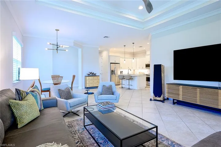 Living room featuring ornamental molding, light tile patterned flooring, and a notable chandelier