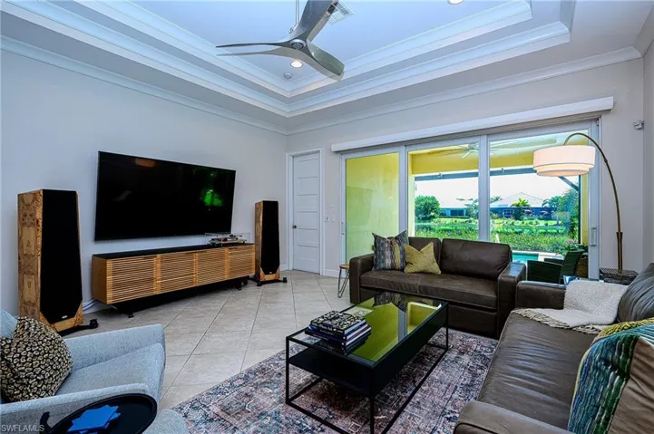 Tiled living room featuring crown molding, ceiling fan, and a raised ceiling