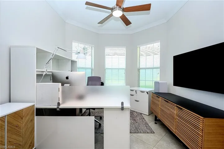 Tiled home office with ceiling fan, a wealth of natural light, and ornamental molding
