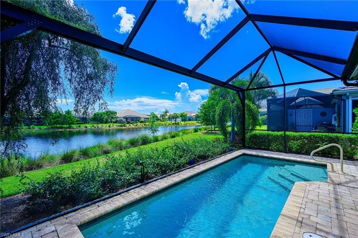 View of pool with a water view and glass enclosure