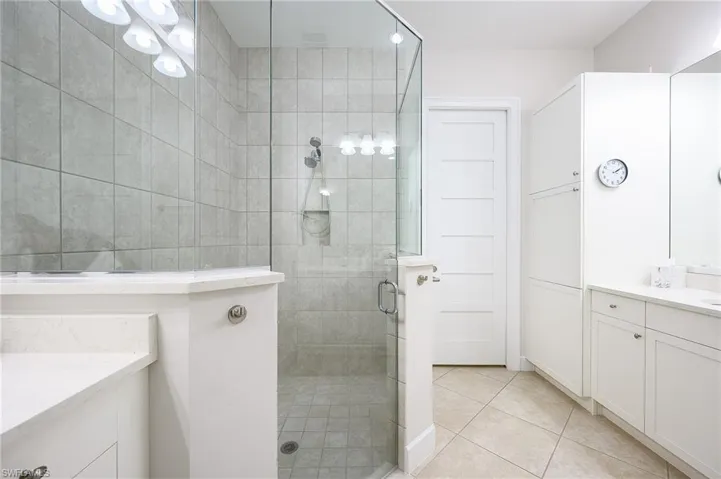 Bathroom featuring vanity, walk in shower, and tile patterned flooring